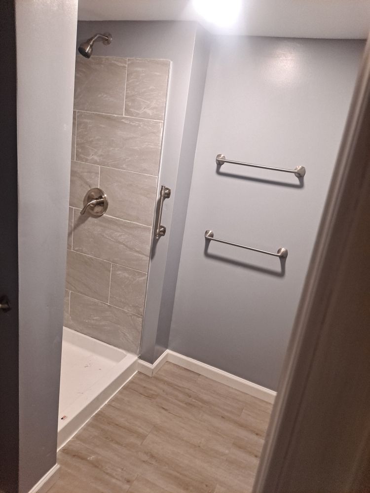 Finished basement bathroom with tiled walk-in shower, new towel bars and wood-look flooring