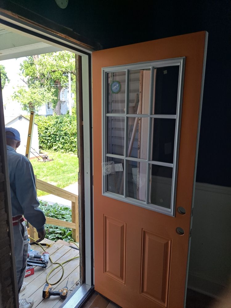 New exterior entry door being installed with contractor working on the porch