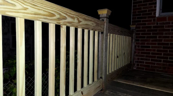 Newly built pressure-treated deck railing attached to a brick home